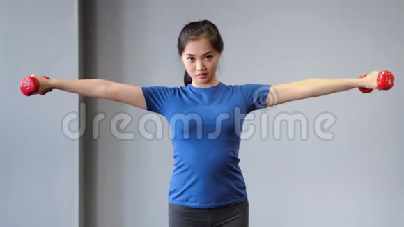 自信的亚洲年轻健身女性使用哑铃做锻炼享受训练视频的预览图