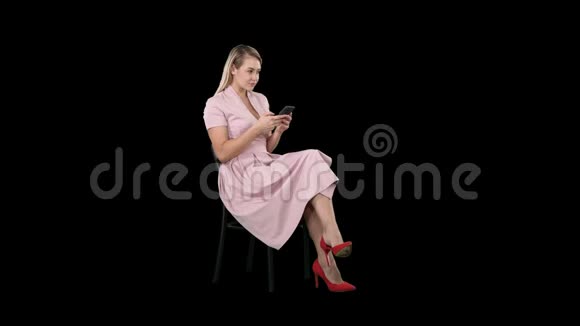 穿着粉色裙子的体贴女人在智能手机上发短信阿尔法频道视频的预览图