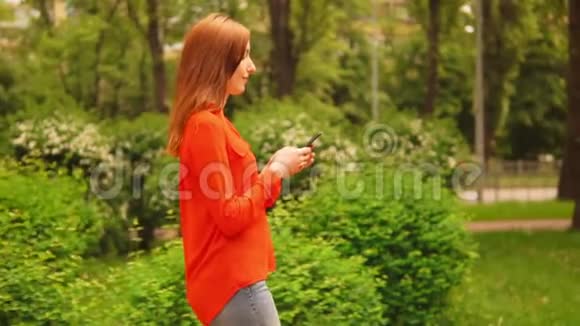 侧视姜女走在街上拿着智能手机视频的预览图