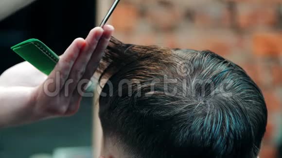 理发师用剪刀在梳子下面理发店理发的人视频的预览图