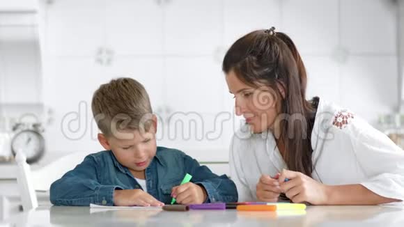 肖像自信的男孩用彩色毡尖笔画在纸上母亲欣赏儿子视频的预览图
