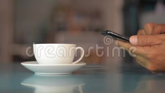 商人在桌子上用智能手机在家里喝一杯咖啡视频的预览图