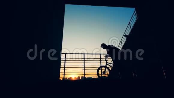 人站在自行车上日落背景慢动作视频的预览图