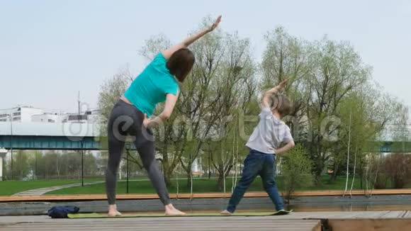 女人和儿子在池塘边做瑜伽户外视频的预览图