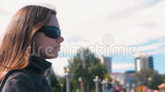 秋天在城市背景上戴太阳镜的年轻黑发女人视频的预览图