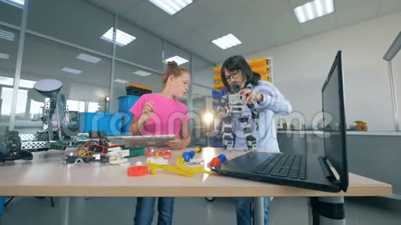 一个男孩修理机器人而一个女孩在实验室里用平板电脑工作现代教育观念视频的预览图