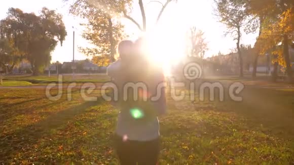 商务女性带着小孩在夕阳的阳光下穿过城市公园视频的预览图