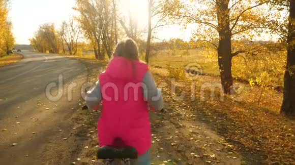 秋天少女牵着双手骑着自行车在褪色的金叶上上路视频的预览图