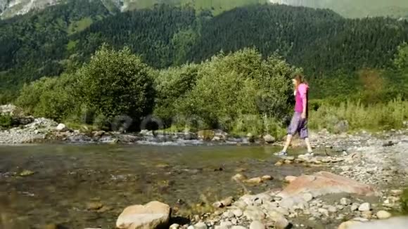女游客在山景背景下穿过小溪视频的预览图