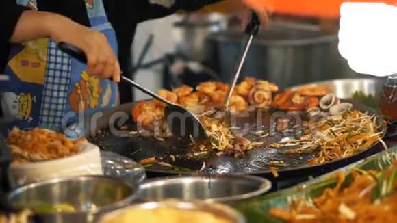 厨师在夜间食品市场上用面条和海鲜烹饪泰国菜美味的亚洲街头美食关门视频的预览图