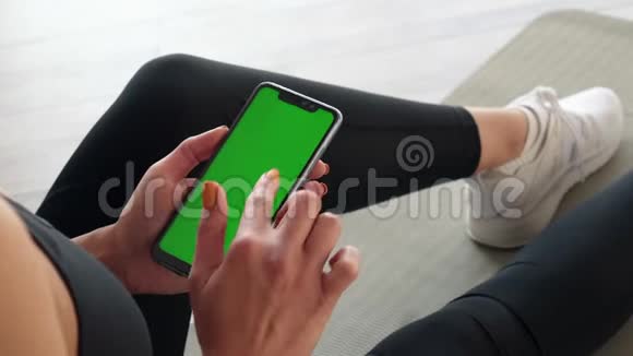 绿色屏幕智能手机手中的运动女性特写视频的预览图