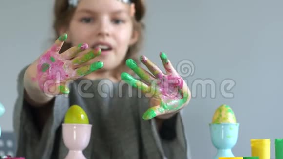 孩子们复活节的创造力一个女孩的特写用多种颜色的油漆弄脏了她的手复活节彩蛋视频的预览图