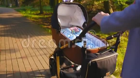 妈妈手里拿着婴儿车手柄妈妈和婴儿车里的婴儿一起散步儿童在现代围猎者视频的预览图