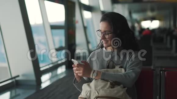 女孩在机场休息室使用智能手机视频的预览图