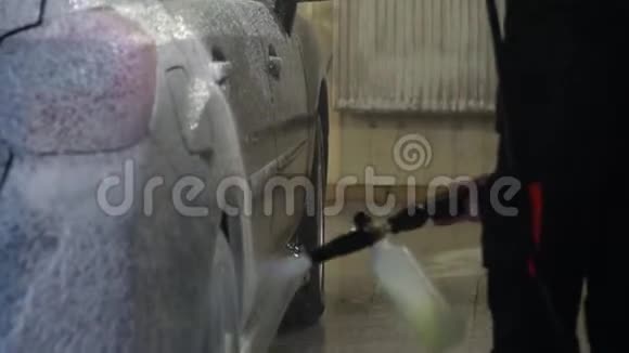 洗车洗车机清洗汽车洗车工人在汽车上涂上泡沫特写镜头视频的预览图