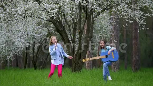 表演两个小女孩在春天在户外闲逛在滑稽剧和模仿流行音乐家的森林里演奏摇滚乐视频的预览图