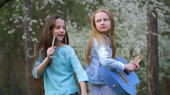 两个女朋友在户外玩得很开心年轻人在森林里享受春日弹吉他的小女孩唱歌视频的预览图