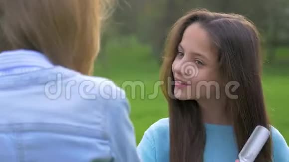 可爱的年轻女孩和她的女朋友聊天梳头做自己的头发快乐和微笑视频的预览图
