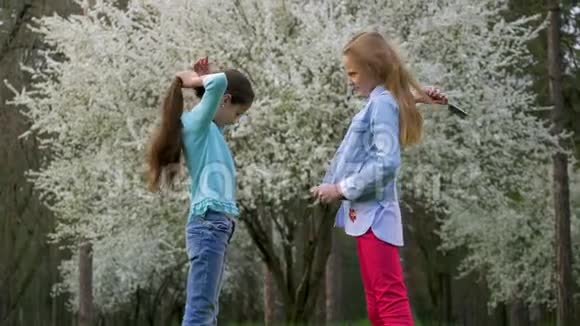 美丽的春天两个可爱的微笑女朋友做发型绽放的花园美容美发护理视频的预览图