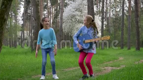 孩子们的户外游戏快乐的女朋友在春天和吉他一起跳到公园里视频的预览图