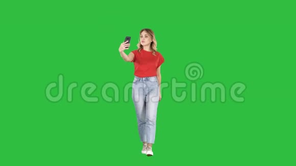 可爱的女孩与金发卷发散步和自拍在绿色屏幕Chroma键视频的预览图