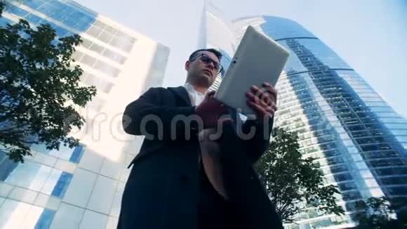 男性成功的金融专家被城市建筑摩天大楼包围红色史诗影院镜头拍摄视频的预览图