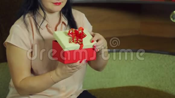 一位戴着圣诞老人帽子的年轻女子打开盒子带来一份圣诞礼物并为之感到高兴视频的预览图