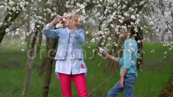 两个度假的学校朋友折断了一棵开花树的树枝游戏和娱乐自然春天视频的预览图