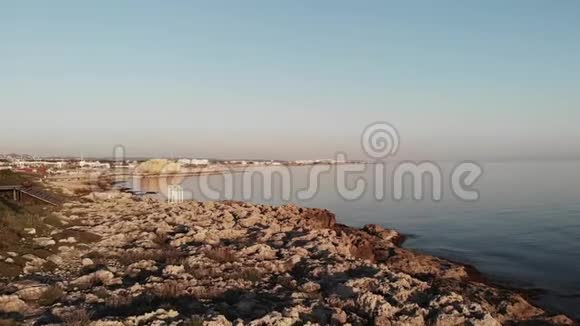 无人机拍摄的岩石悬崖海滩与白色纪念碑在帕福斯塞浦路斯城与平静的看到和城堡的背景视频的预览图