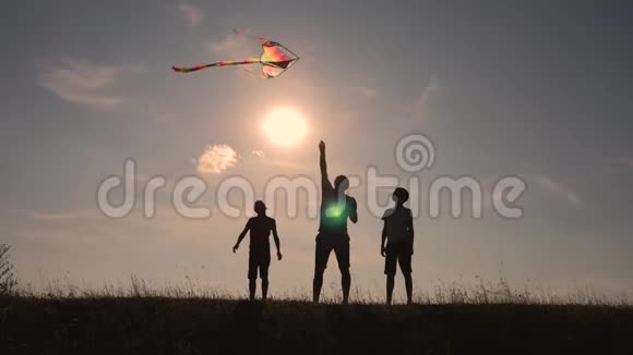 幸福一家人在户外玩耍放风筝日落时带风筝的儿童剪影团队合作团队合作视频的预览图