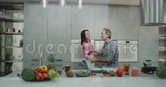 美丽的成熟夫妇在厨房里边做边做边做健康的晚餐现代化的厨房设计大厨房视频的预览图