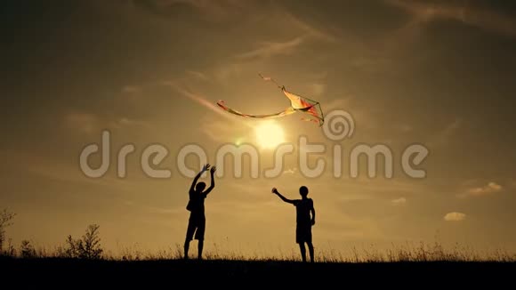 幸福一家人在户外玩耍放风筝日落时带风筝的儿童剪影团队合作团队合作视频的预览图