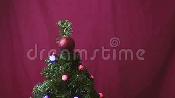 圣诞树上装饰着一个闪闪发光的花环和一个红色闪亮的球视频的预览图