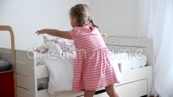 一个3岁的女孩在儿童房间里铺床视频的预览图