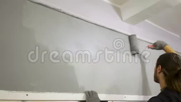 男画家建筑工画一面灰色的墙特写修补视频的预览图