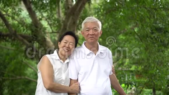 在绿树背景下一对亚洲老夫妇笑得开心视频的预览图