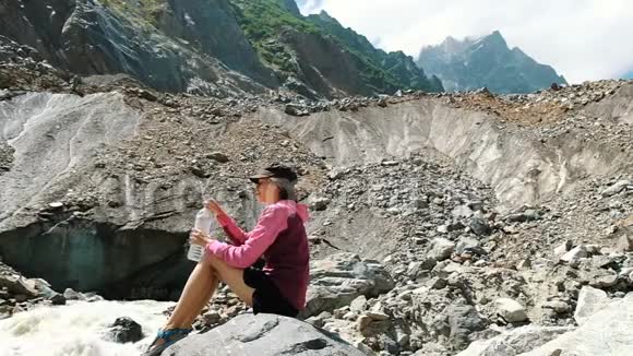 女游客从山里的瓶子里喝水慢动作视频的预览图