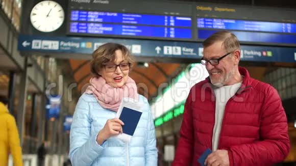 成熟的女人拿着护照和机票为即将到来的旅行感到高兴在火车站的夫妻旅费视频的预览图