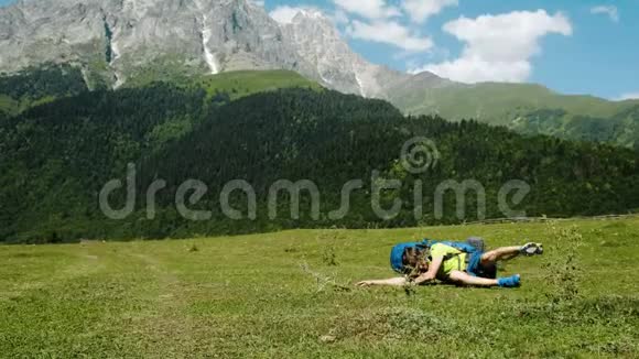带着一个大背包的游客在一座美丽的山的背景下从地面上站起来视频的预览图