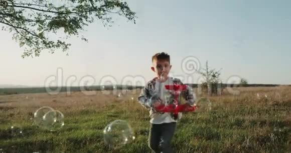 一个三岁的可爱男孩在大自然的气泡中行走拿着一架红色的大飞机视频的预览图