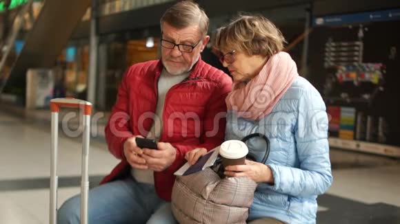 几个成熟的人咨询等待火车的智能手机丈夫和妻子坐在火车上视频的预览图