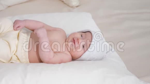 戴着帽子微笑的宝宝躺在白色柔软的床上视频的预览图