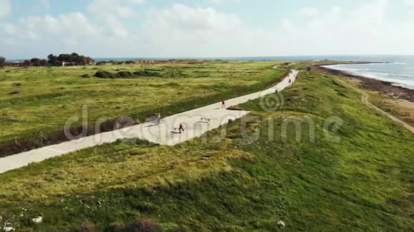 两名骑自行车的人沿着海滨海岸线和行人的空中射击帕福斯塞浦路斯骑自行车的人可以一起娱乐视频的预览图