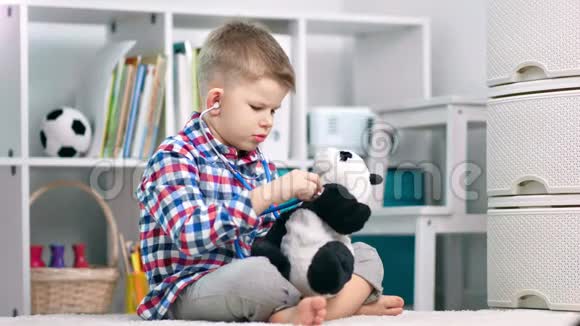 一个学龄前的男孩和他的熊猫熊在玩医生视频的预览图