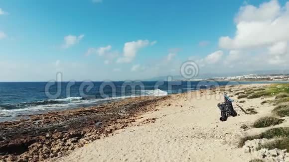 肮脏的海滩上堆满了塑料瓶和金属建筑海浪撞击岩石海滩的空中景色暴风海视频的预览图