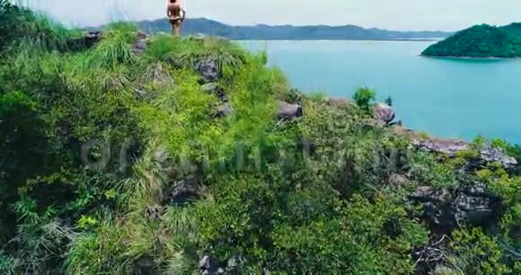 空中一个女孩站在山顶俯视海滩视频的预览图