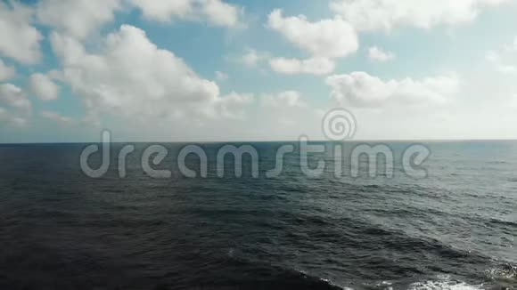 蓝天和云彩的海洋海平线的鸟瞰图强烈的海浪撞击岩石海滩形成泡沫和飞溅视频的预览图