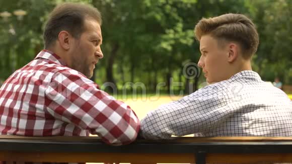 十几岁的儿子在公园的长椅上和爸爸说话爸爸支持他的孩子视频的预览图