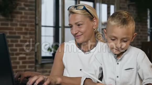 一位忙碌美丽的中年商业女性在笔记本电脑上工作时的肖像当她可爱的小孙子有什么东西时视频的预览图