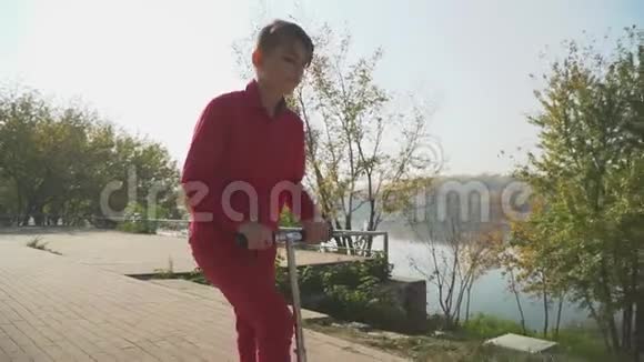 穿红色衣服的男孩在公园里骑滑板车这孩子积极地把时间花在户外慢动作视频的预览图
